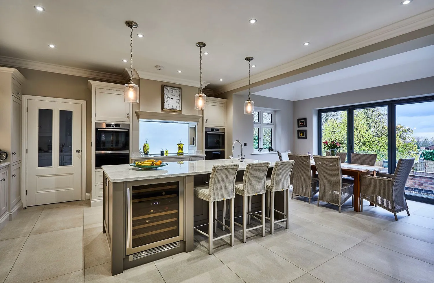 Kitchen with grey cabinets, a white island and pendant lights