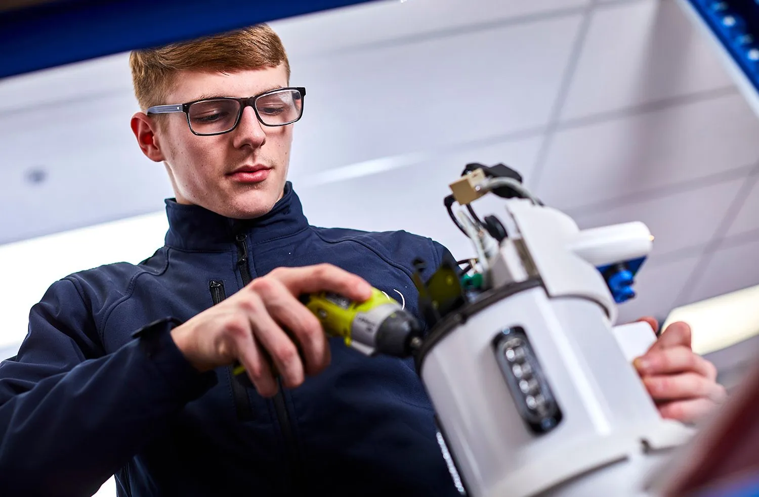 Young engineer in glasses fitting a part to a CCTV camera unit