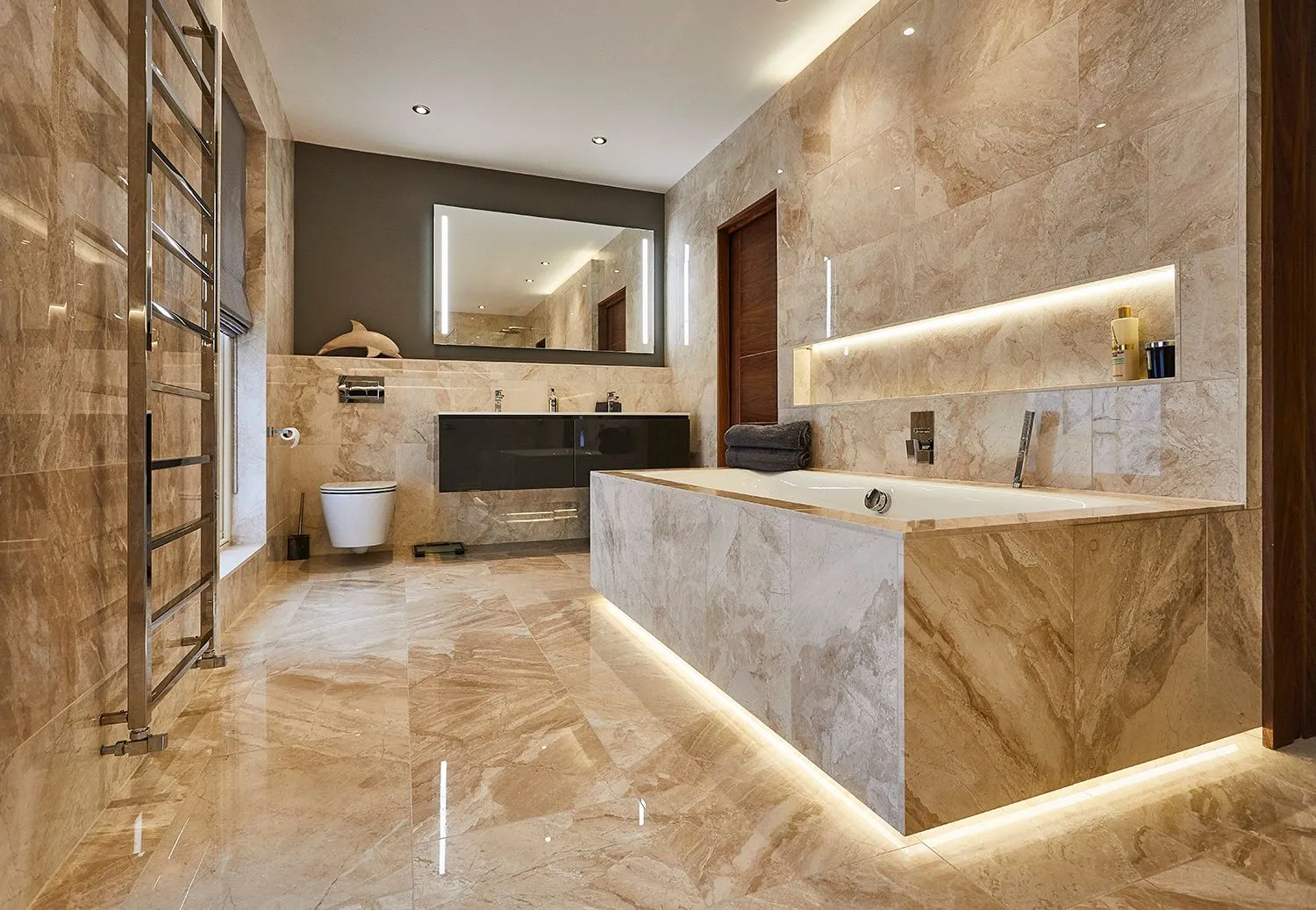 Marble bathroom with a lit vanity and freestanding bath