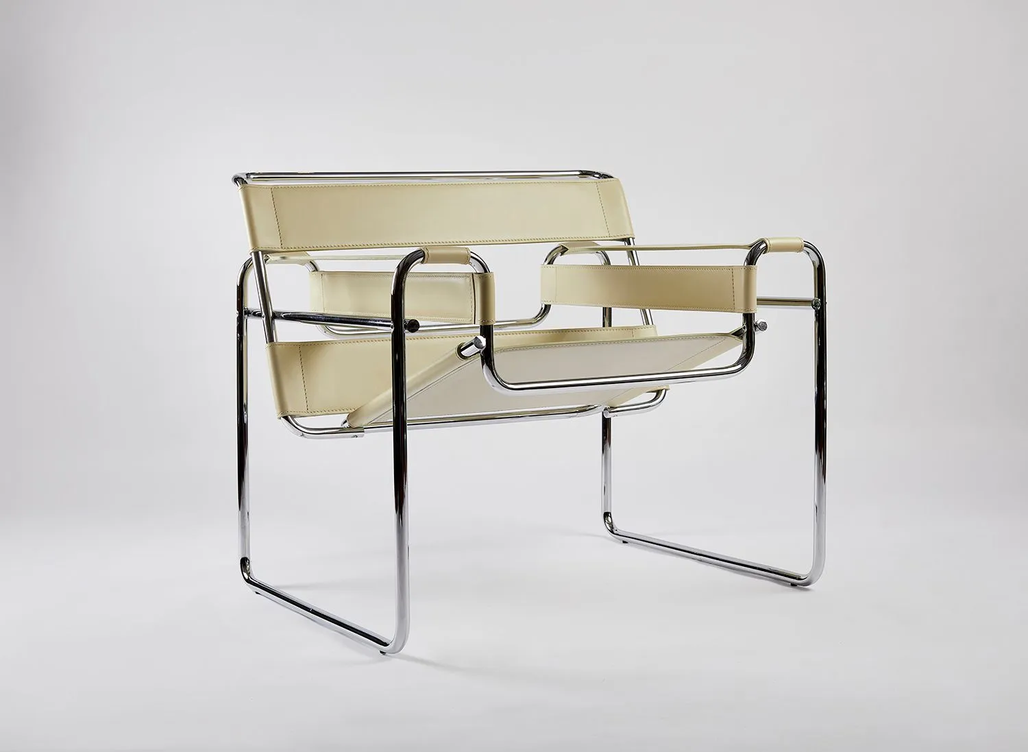 Chrome-framed Wassily chair with cream leather straps on a grey seamless backdrop