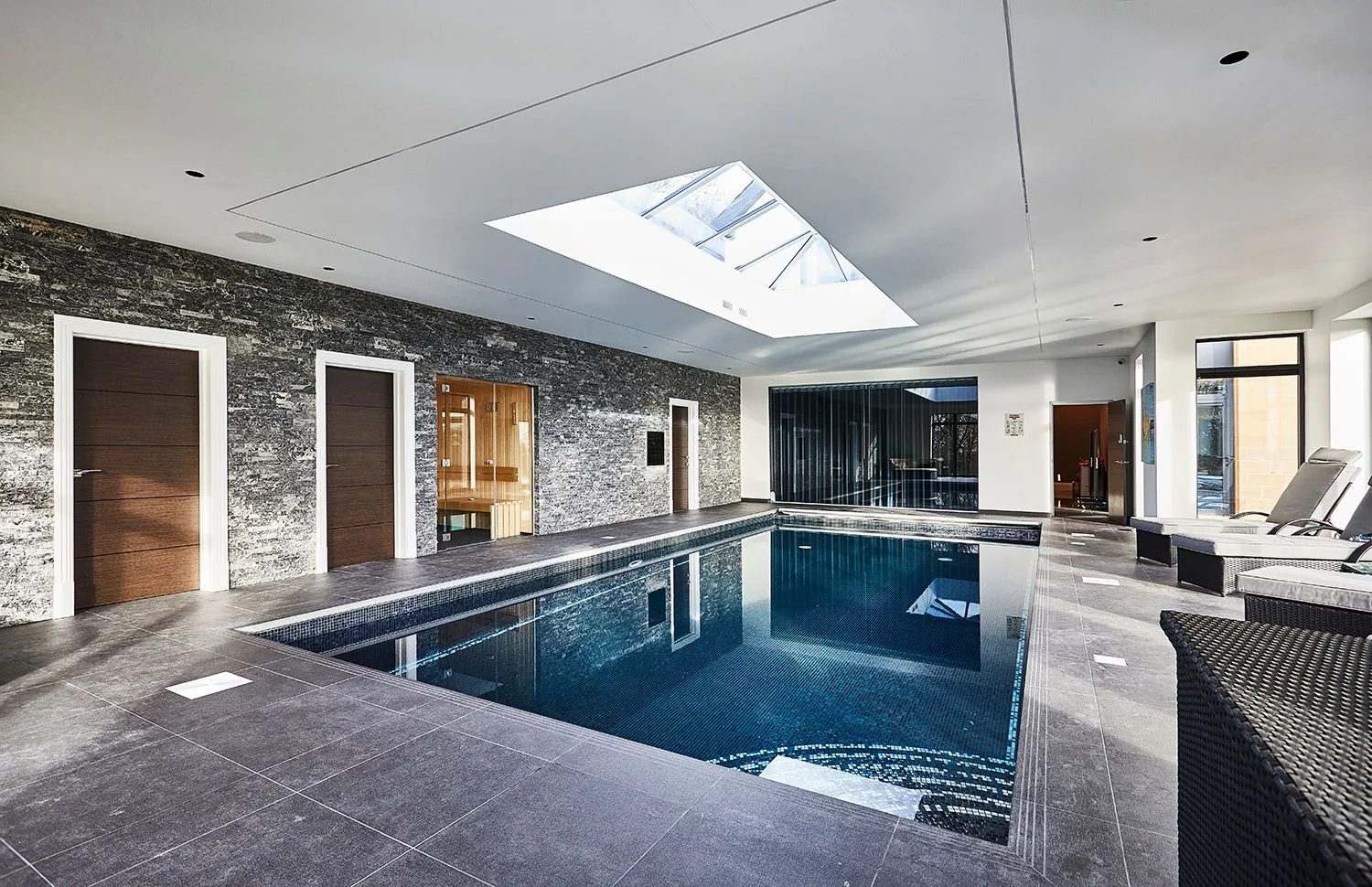 Indoor swimming pool with a stone wall and roof lantern