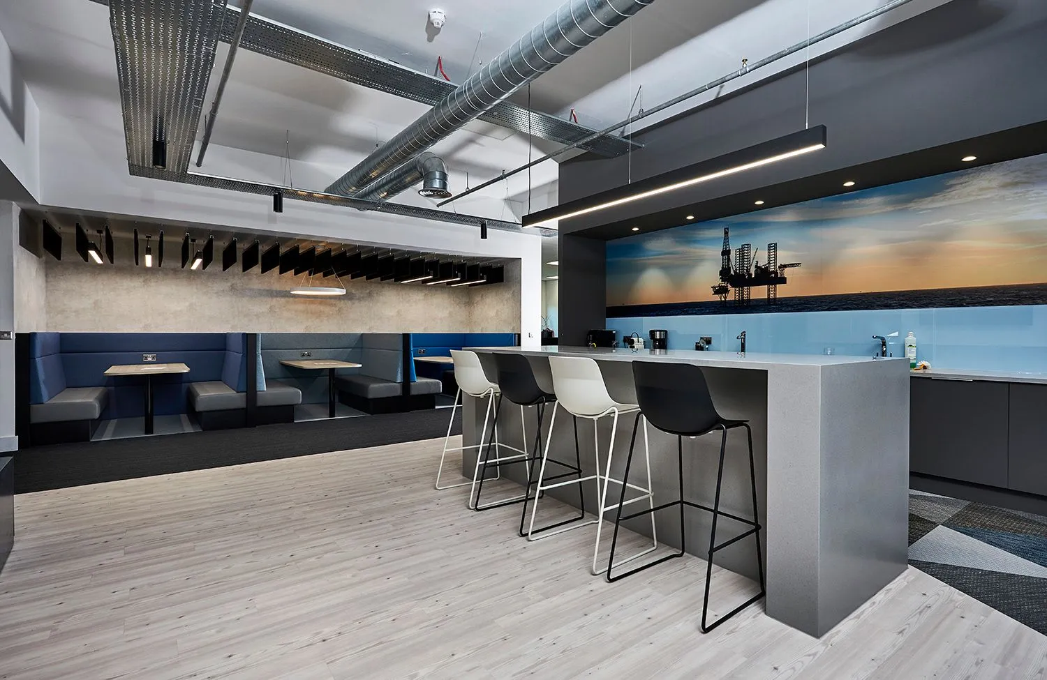 Office kitchen and breakout area with a long white island and blue banquette seating