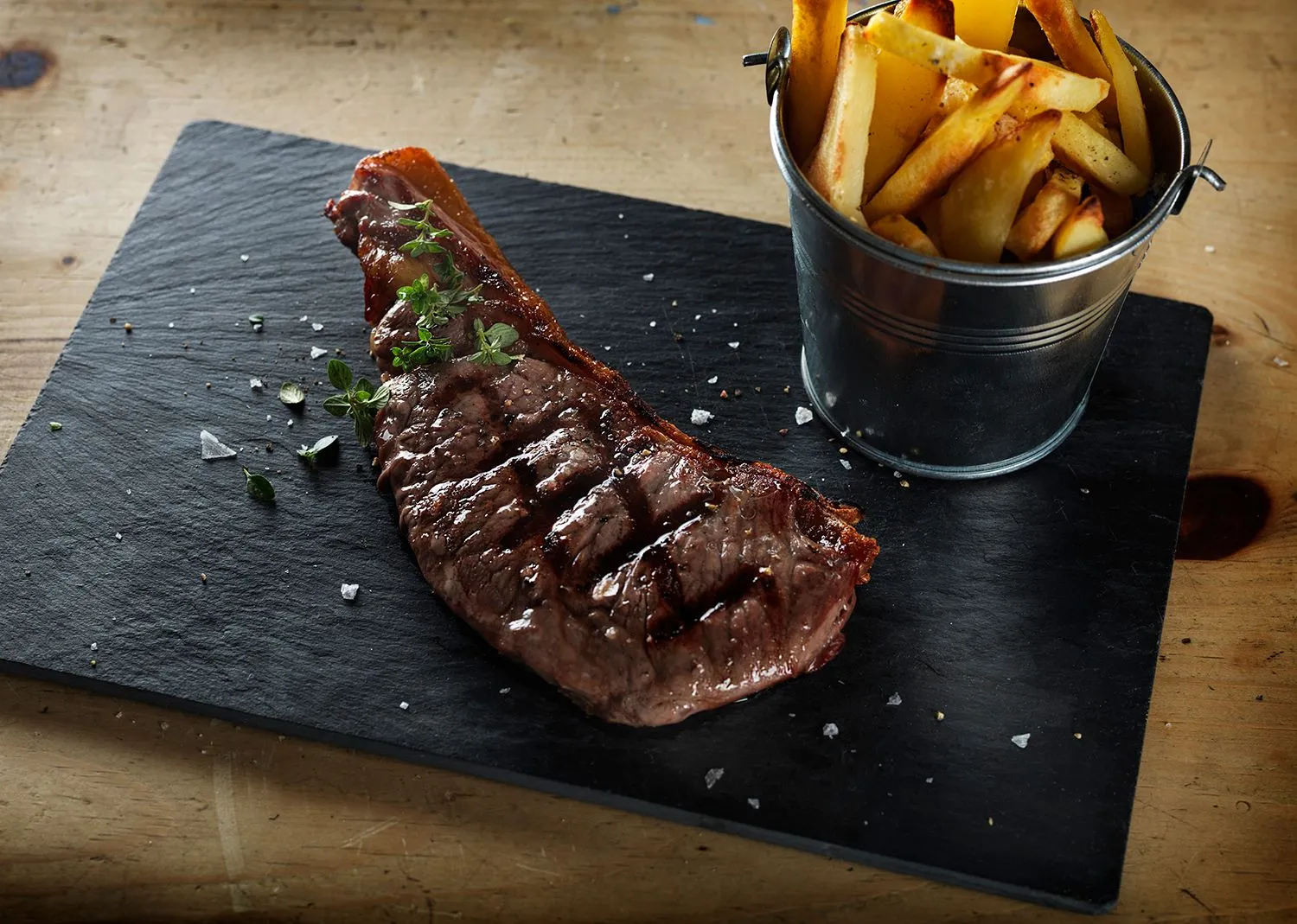 Chargrilled sirloin on slate with a bucket of fries