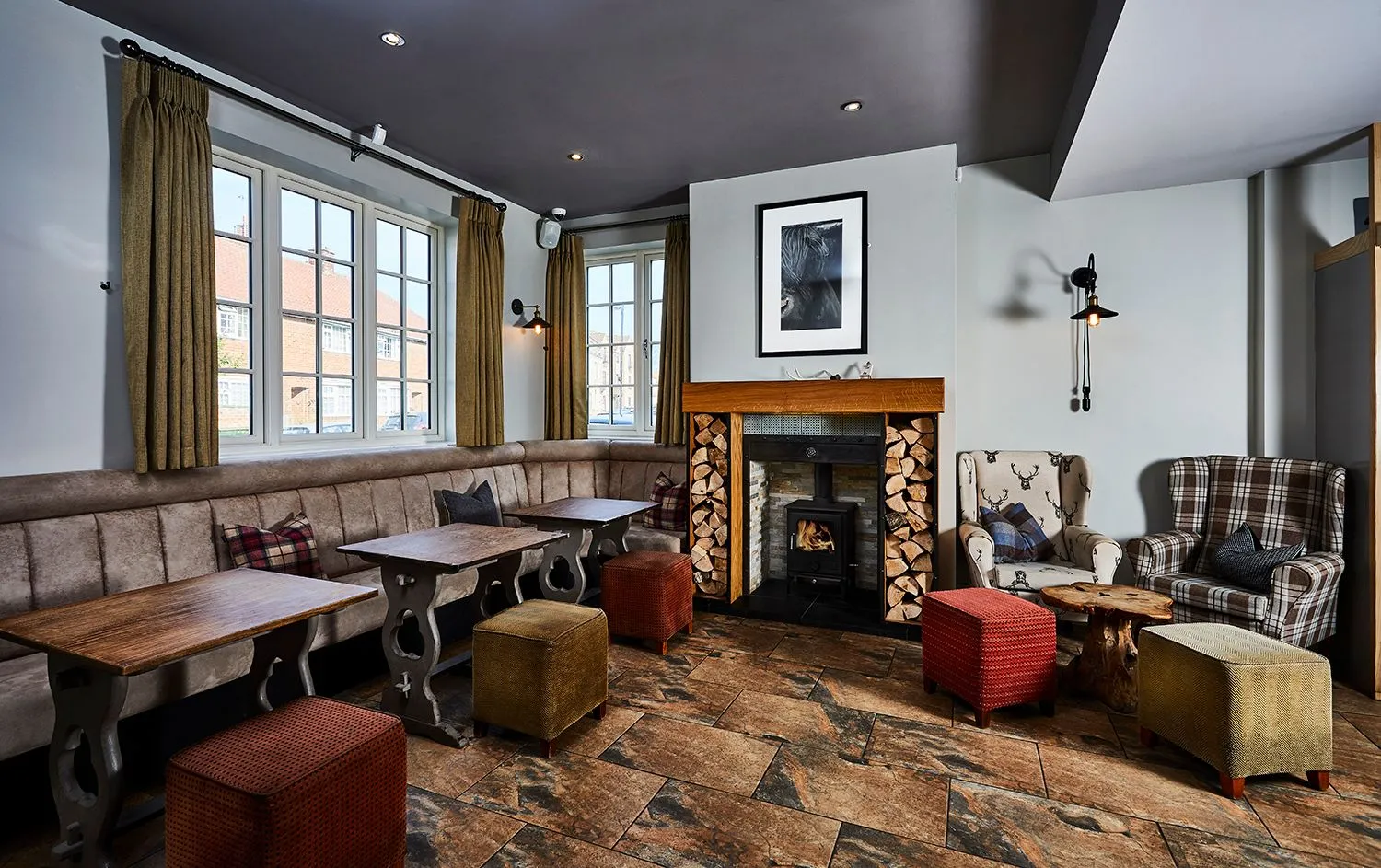 Pub interior with a log burner, timber tables and upholstered stools