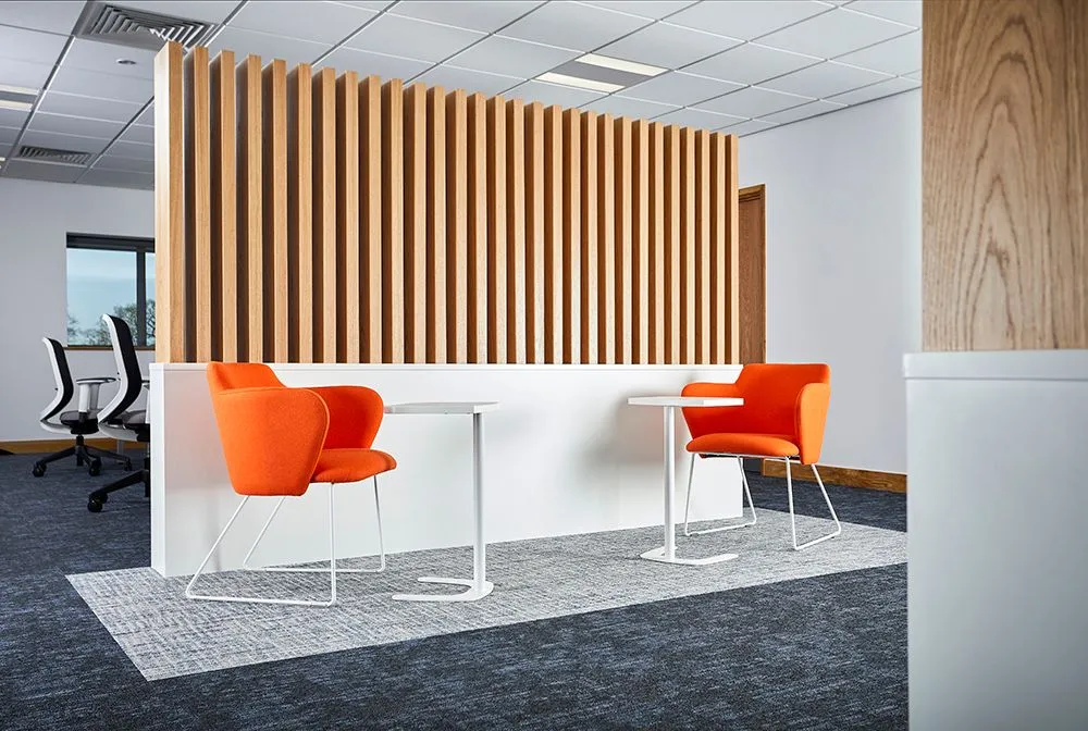 Office breakout space with orange chairs and a slatted timber screen