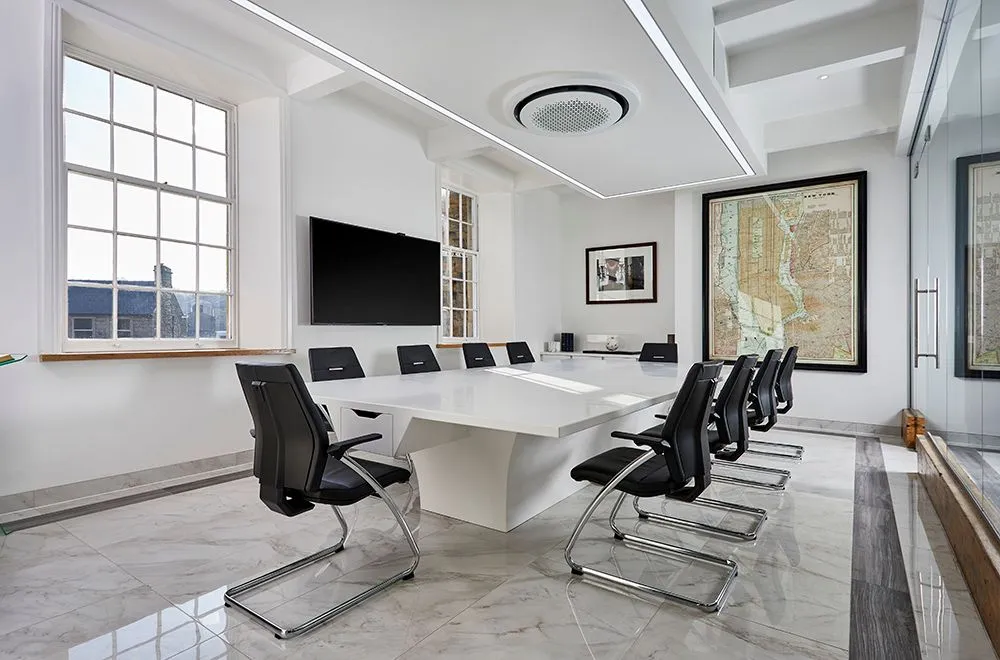 Bright boardroom with a white table, black chairs and a framed map