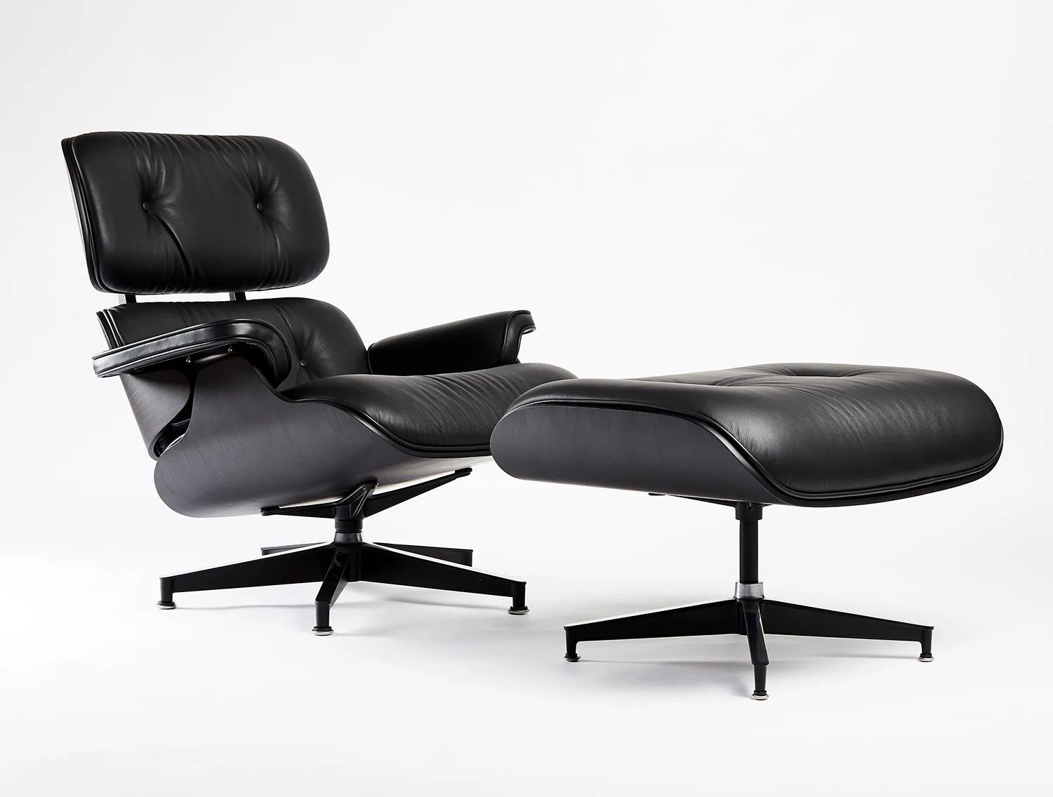Lounge chair and ottoman in black leather on a white seamless backdrop