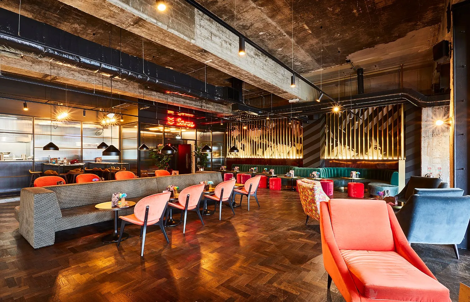 Everyman bar with warm lighting, coral armchairs and a parquet floor