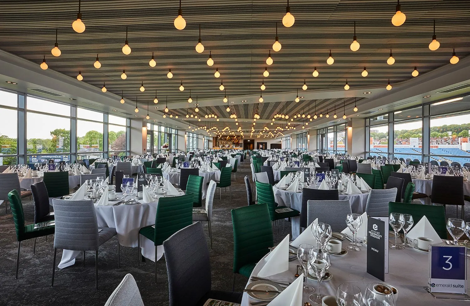 Banqueting suite laid for dinner beneath festoon lighting