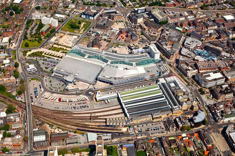 Aerial view over a northern town centre, railway station and retail park