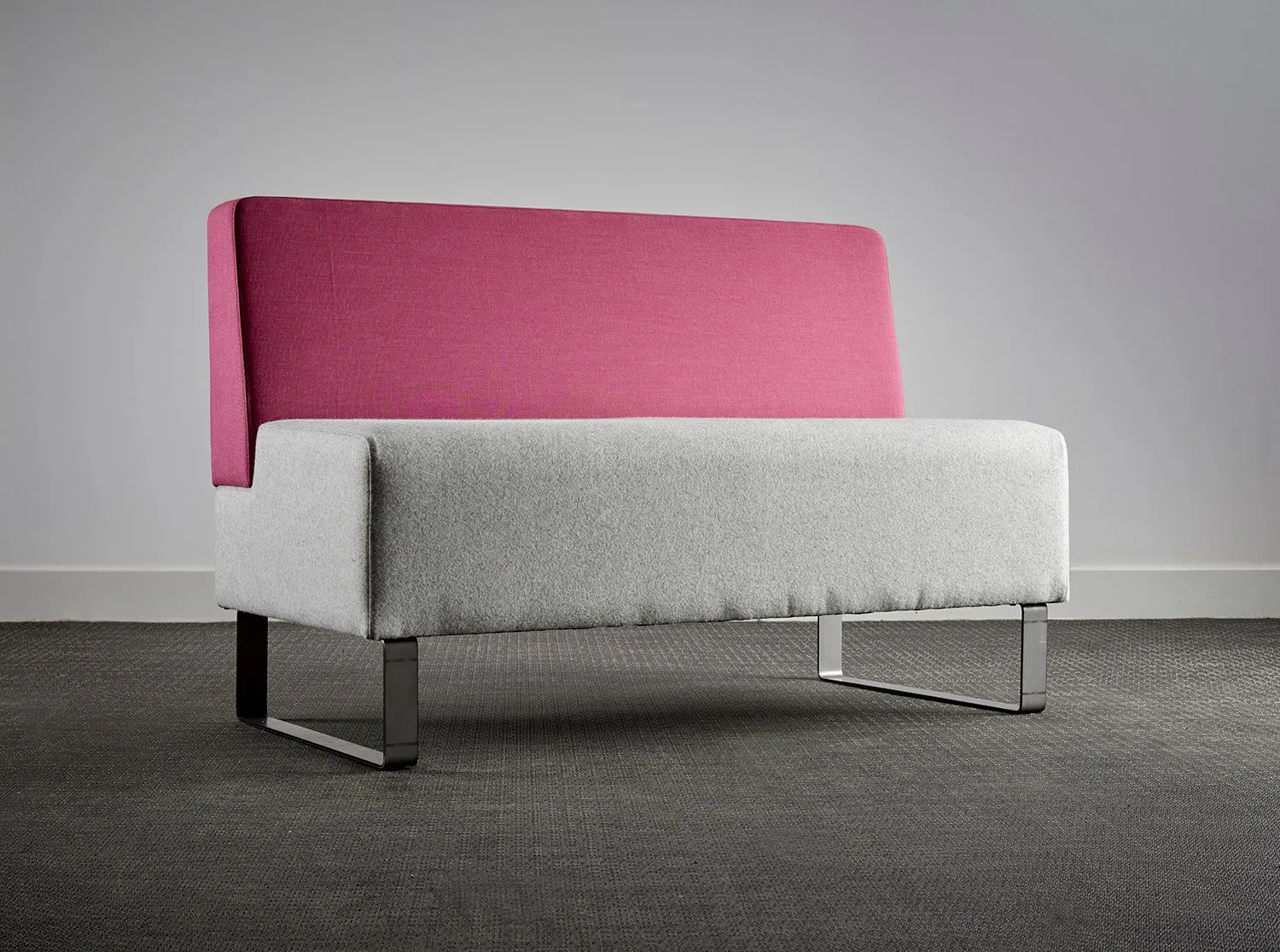 Two-seat sofa with a pink back and grey seat on a studio backdrop