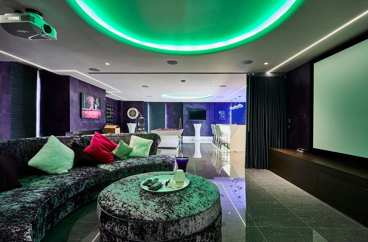 Home cinema room with green ceiling lighting and a velvet sofa