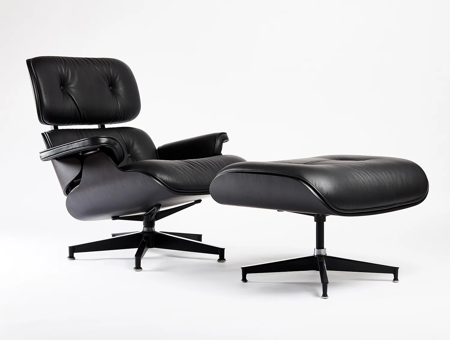 Black leather lounge chair and ottoman on a white backdrop