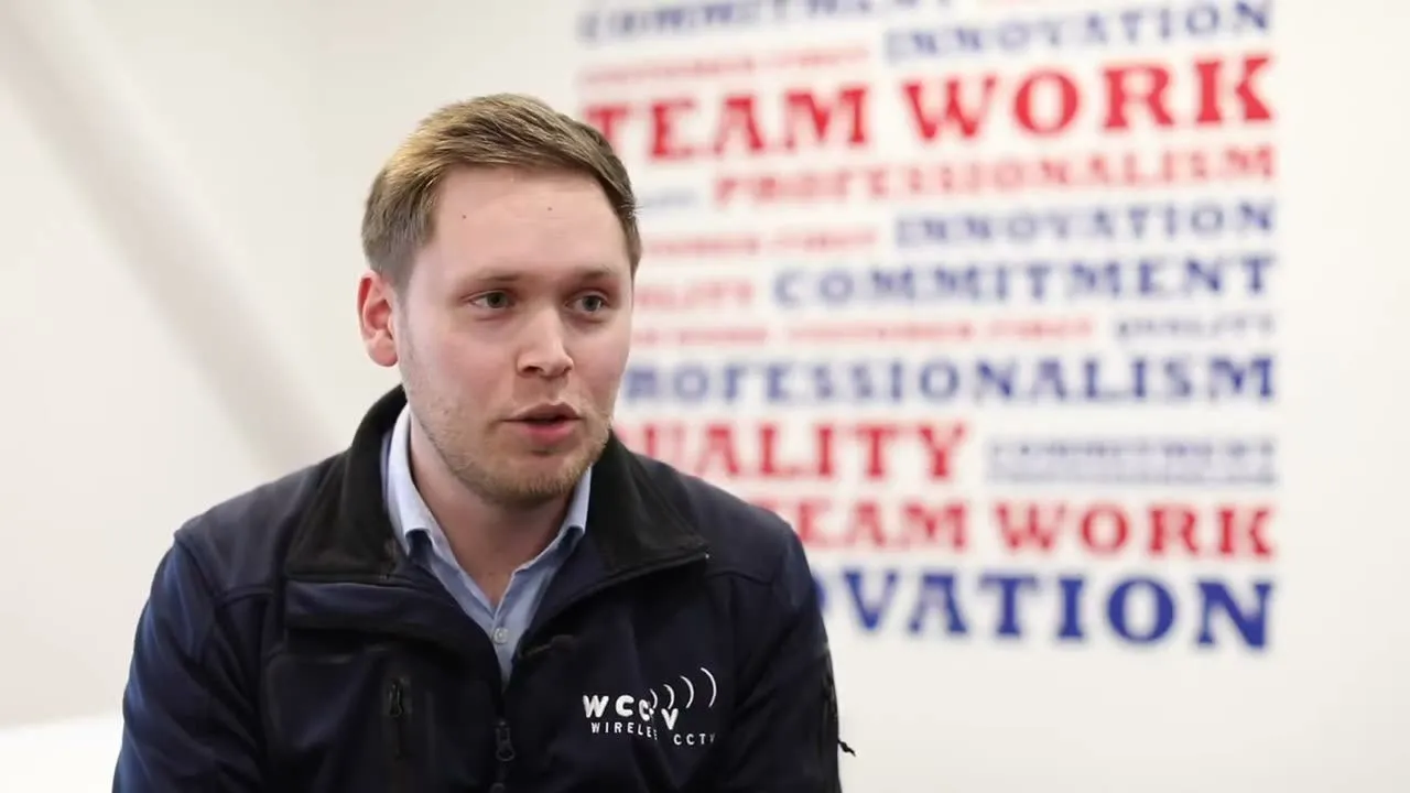 A young engineer being interviewed in front of a wall of company values