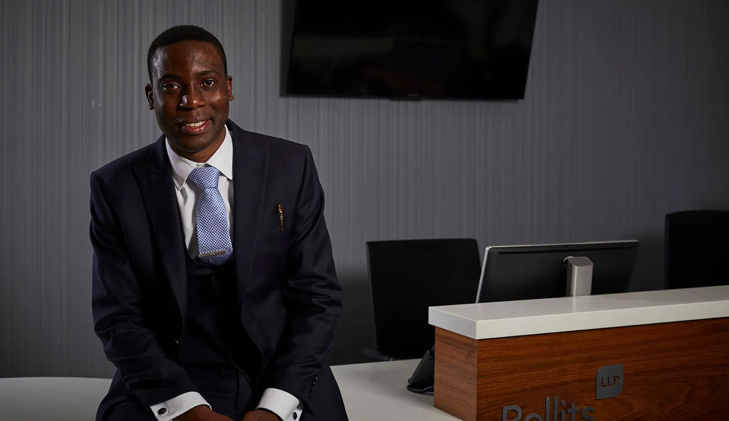 Young man in a navy suit seated in an office reception