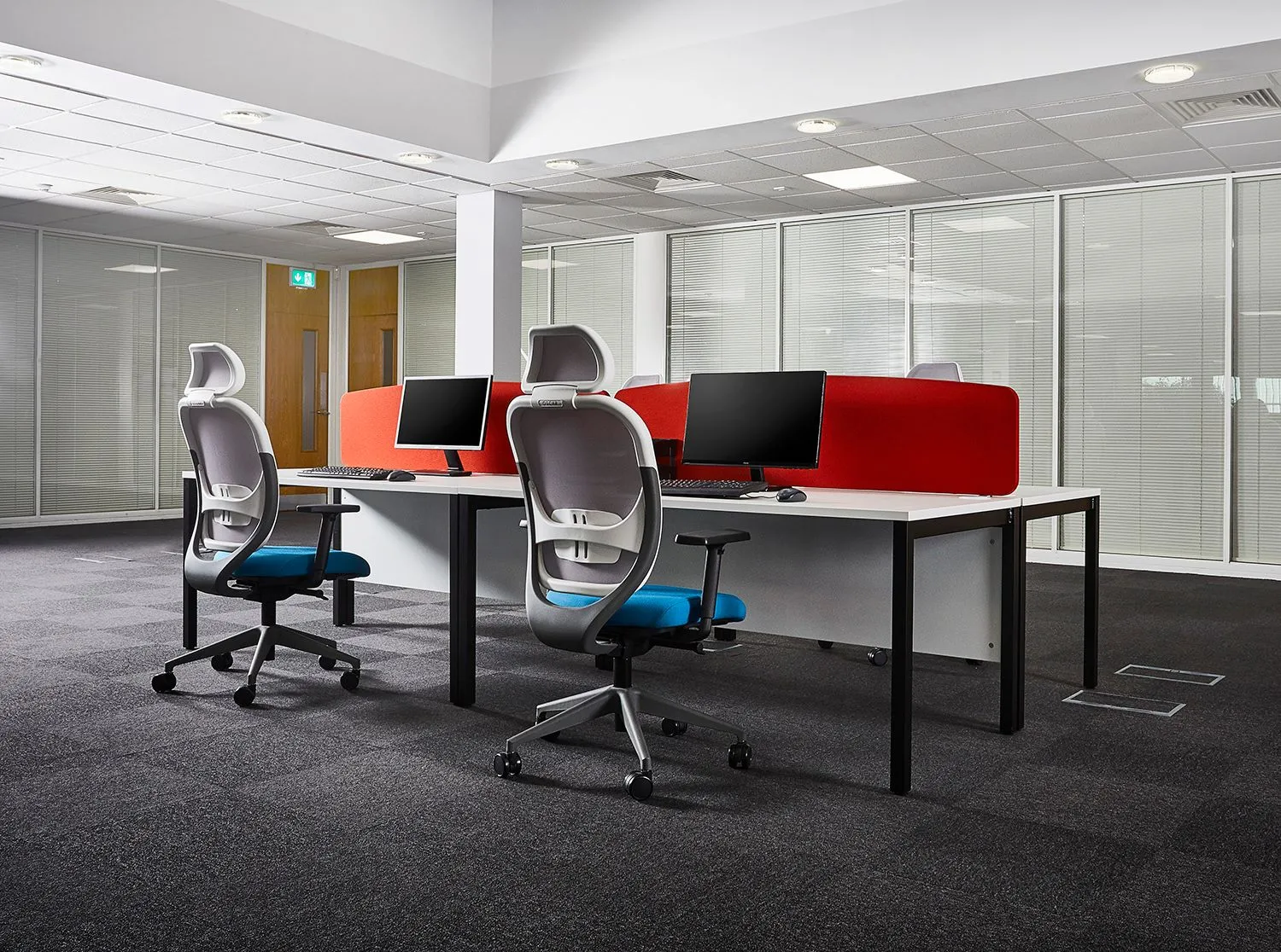 Open-plan office with red desk screens and rows of task chairs
