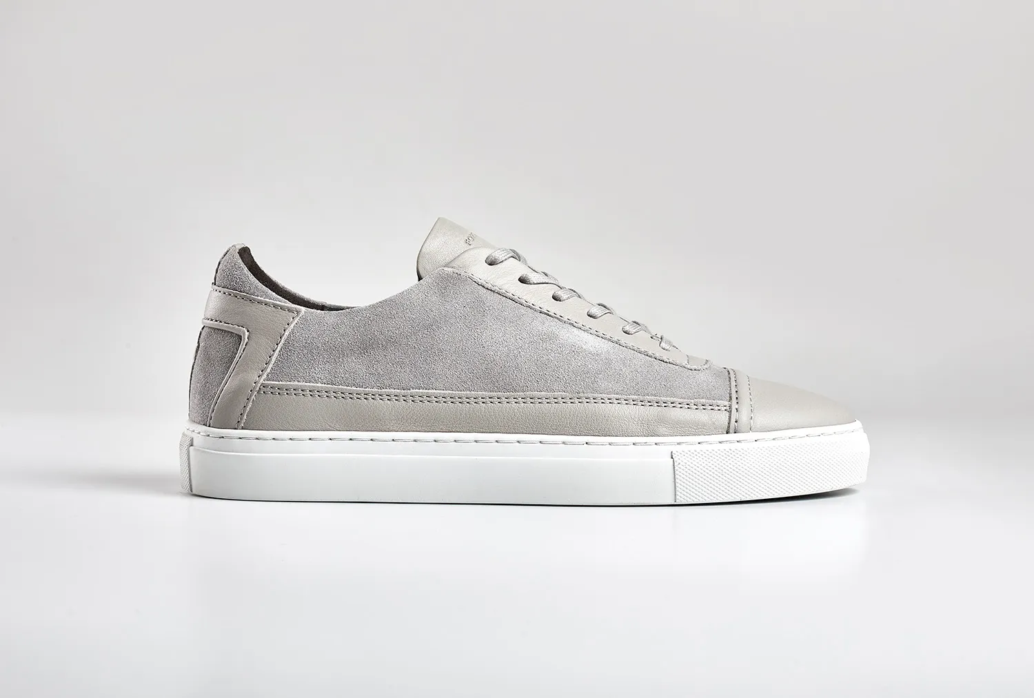 Grey suede trainer photographed side-on against white