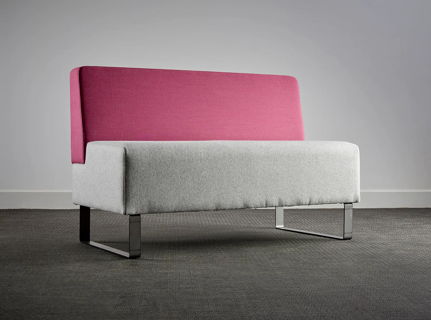 Two-seat sofa with a pink back and grey seat on a studio backdrop