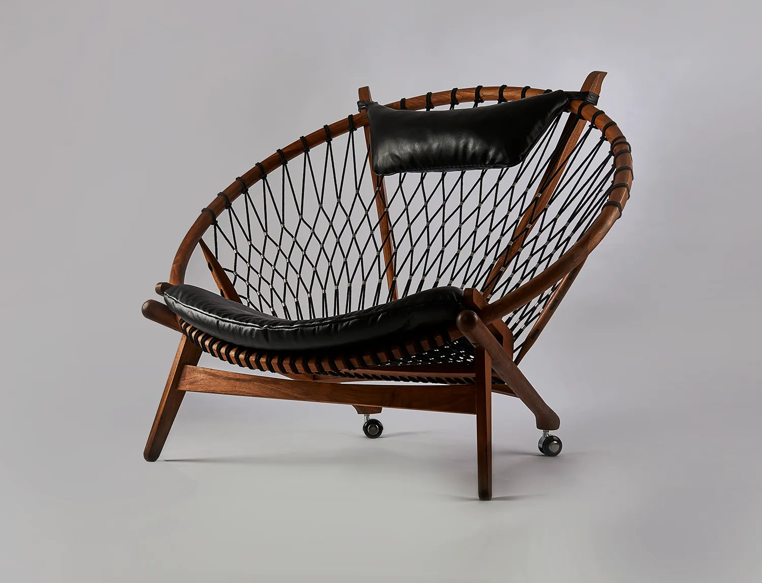 Hoop chair with a rope weave and leather cushions on a grey backdrop
