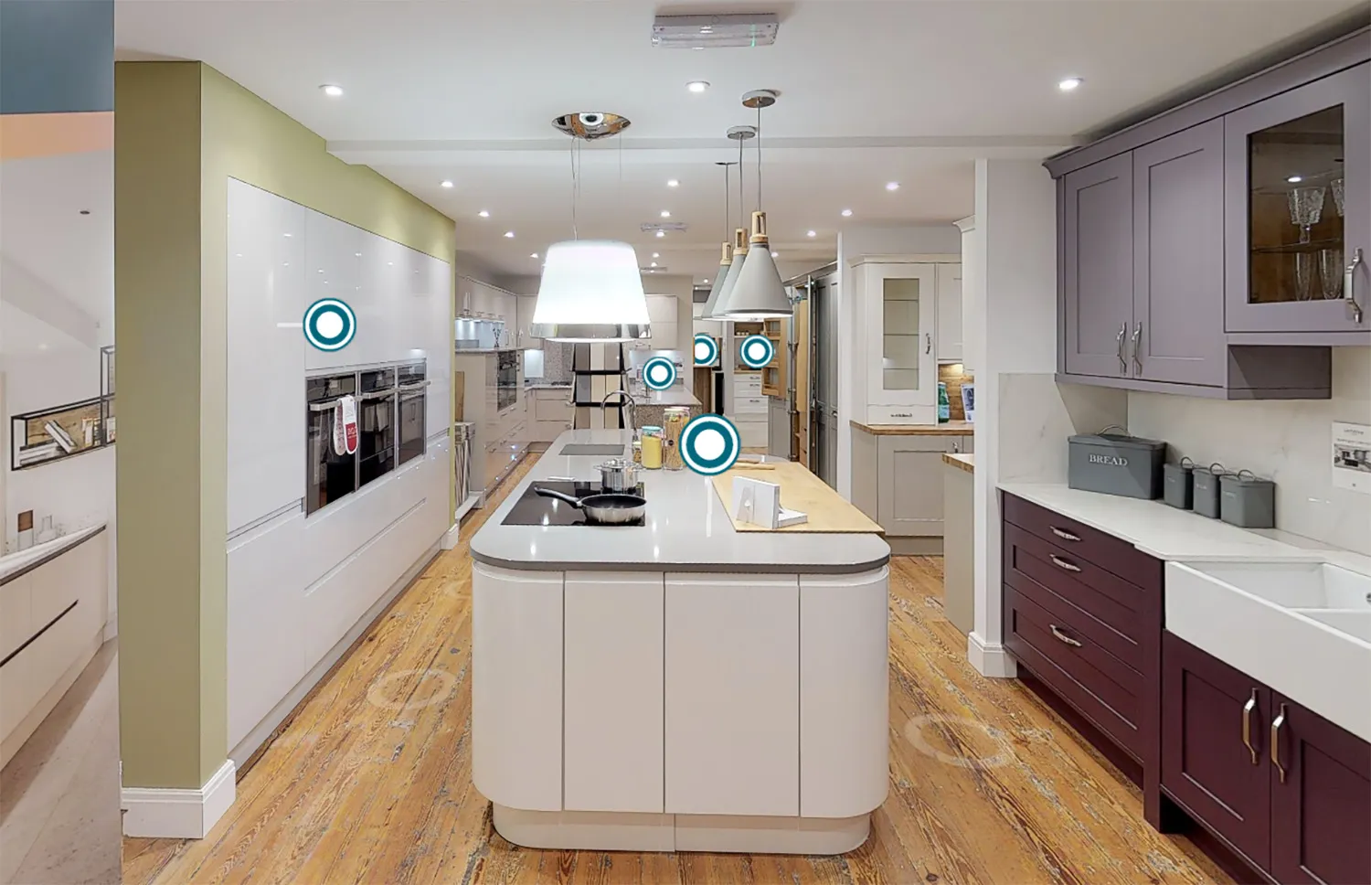 Kitchen showroom with a white island, pendant lights and aubergine cabinets